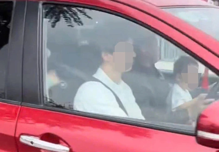 Nam tài xế ôm một trẻ nhỏ trong lòng khi ngồi lái ô tô, tay đứa trẻ cầm vào vô lăng